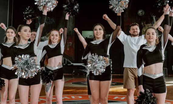 Energetic cheerleading team performing indoors with pompoms and uniforms.